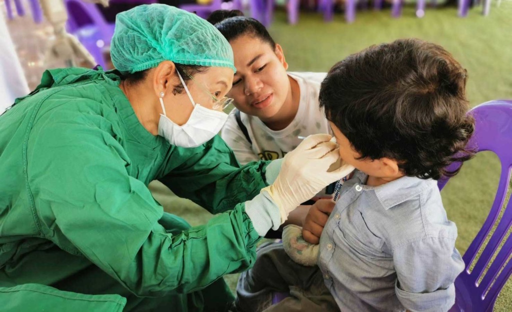 Kemporn giving dental exam to a child