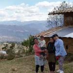 Two women and child outside a house in the mountains