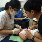 Dr. Oliveros-Villarico (left) performs an oral health exam