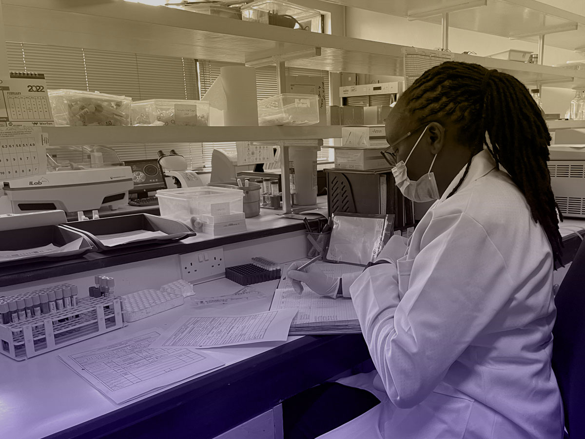 young woman in mask sitting at a lab bench